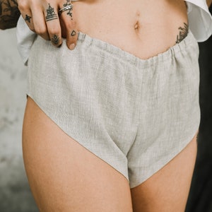 Pu&ograve; includere: Pantaloncini in lino grigio chiaro dalla vestibilit&agrave; rilassata. I pantaloncini hanno un design a vita alta e un aspetto morbido e strutturato. Il tessuto sembra leggero e traspirante, adatto per la stagione calda. I pantaloncini sono di colore neutro.