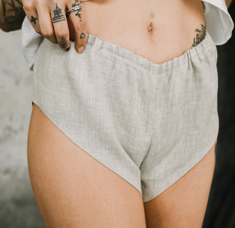 Pu&ograve; includere: Pantaloncini in lino grigio chiaro dalla vestibilit&agrave; rilassata. I pantaloncini hanno un design a vita alta e un aspetto morbido e strutturato. Il tessuto sembra leggero e traspirante, adatto per la stagione calda. I pantaloncini sono di colore neutro.
