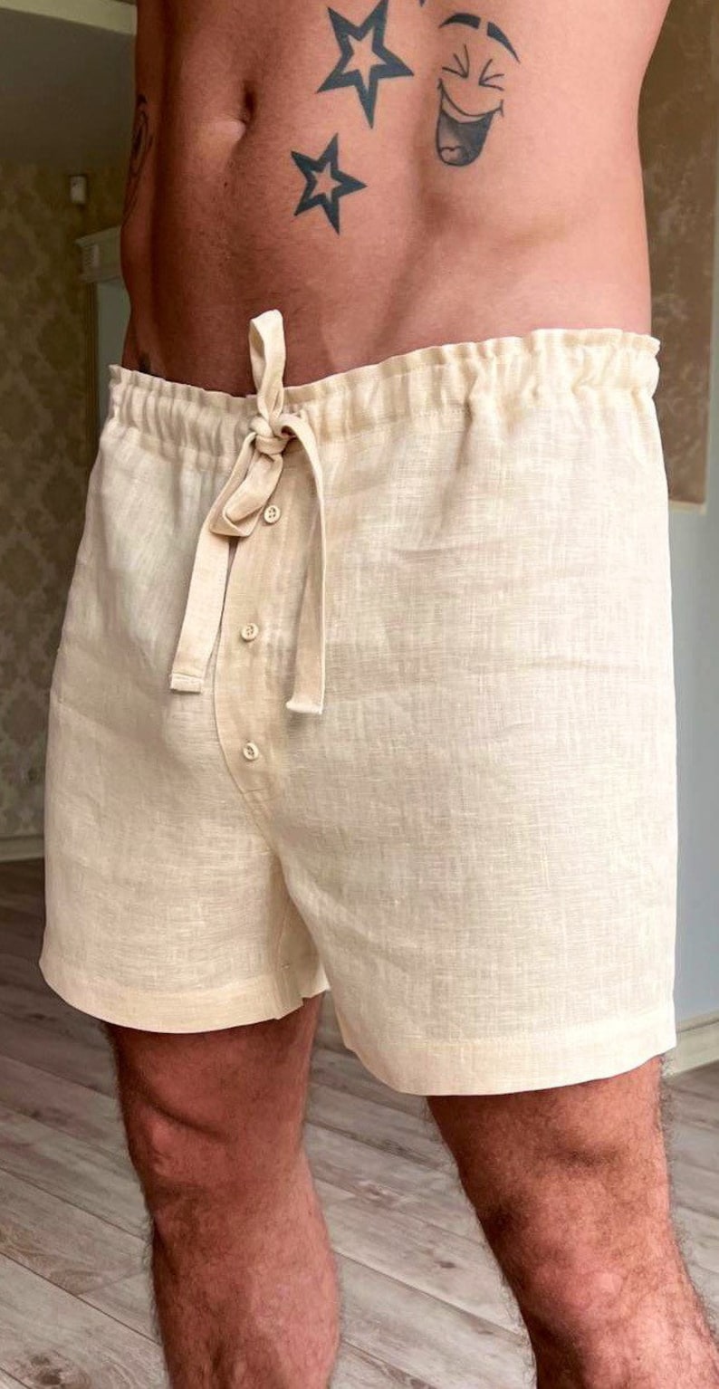K&ouml;nnte beinhalten: Beigefarbene Leinenhose mit Kordelzugbund und Knopfleiste. Die Hose hat eine lockere Passform und ist aus einem leichten Stoff gefertigt.