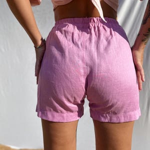 Pu&ograve; includere: Pantaloncini rosa chiaro con vita elasticizzata e taglio dritto semplice. Il capo &egrave; realizzato in un tessuto testurizzato con motivi di trama visibili, offrendo un look casual con un orlo pulito e una lunghezza a met&agrave; coscia.