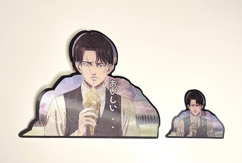 以下が含まれることがあります： アイスクリームを食べている黒髪男性のアニメキャラクターのステッカー2枚。大きい方のステッカーには「おいしい」という日本語が書かれています。