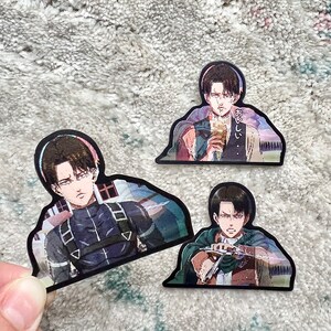 以下が含まれることがあります： 白黒のアニメキャラクターのステッカー3枚。最初のステッカーは、黒髪のキャラクターが真剣な表情をしている。2枚目のステッカーは、黒髪のキャラクターが驚いた表情をしている。3枚目のステッカーは、黒髪のキャラクターが強い決意の表情をしている。