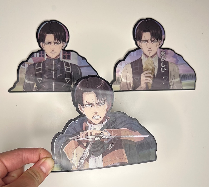以下が含まれることがあります： 黒髪の若い男性が真剣な表情をした、アニメキャラクターのステッカー3枚。ステッカーは白い背景に印刷されており、光沢のある仕上げになっています。