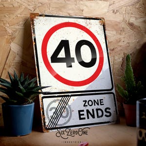 May include: A white metal sign with a red circle and the number 40 in black. The sign says "Zone Ends" in black text. The sign has a distressed, rusty look.