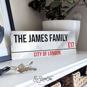May include: White metal sign with black text that reads "The James Family" and red text that reads "City of London" and "E17".