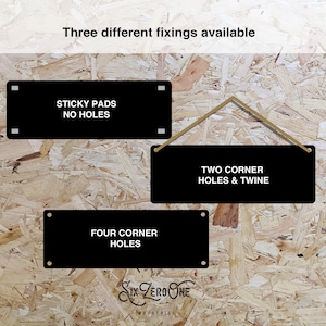 May include: Three different ways to hang a sign: sticky pads with no holes, two corner holes with twine, or four corner holes. The sign is black with white text.