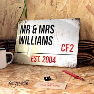 May include: White metal sign with black text that reads "MR & MRS WILLIAMS CF2 EST. 2004".
