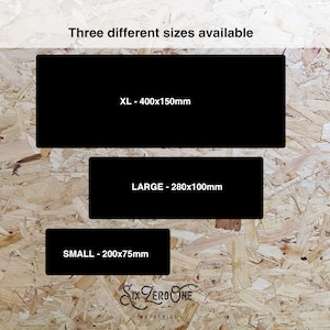 May include: Three different sizes of a black rectangular sign with white text. The text reads "XL - 400x150mm", "LARGE - 280x100mm", and "SMALL - 200x75mm". The signs are on a wood-grain background.