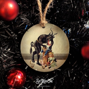 May include: Round Christmas bauble featuring a vintage illustration of a black devil with a long tongue, holding a chain and approaching two children. The devil is wearing a red collar and has horns. The children are dressed in blue and white clothing and are holding a basket of apples. The bauble has a rustic, distressed look and is decorated with glitter.
