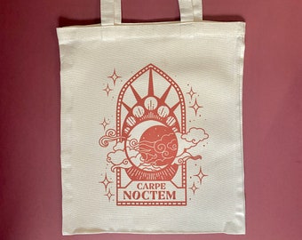 May include: A white tote bag with a red design featuring a crescent moon, stars, and clouds in a window frame. The text "CARPE NOCTEM" is printed below the design.