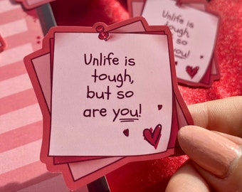 May include: Pink and red motivational note cards with the text "Unlife is tough, but so are you!" on each card. The cards are stacked on top of each other and have a heart drawn on the bottom card.