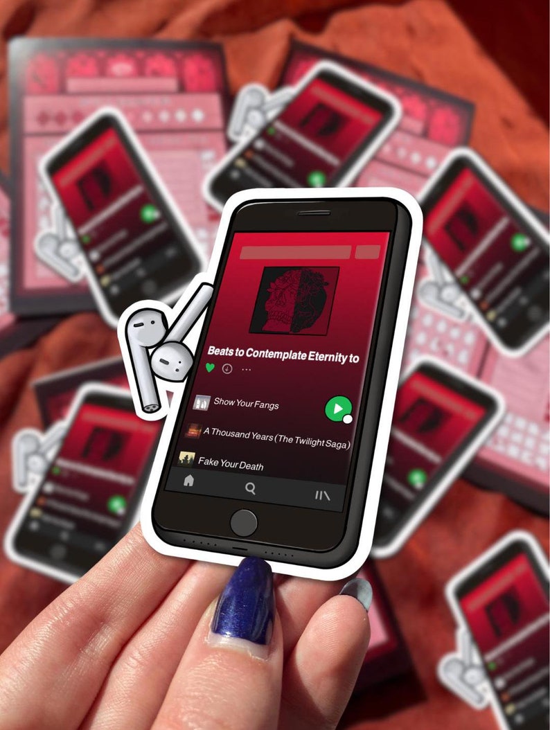 Puede incluir: Una pegatina blanca con un contorno negro de un tel&eacute;fono inteligente reproduciendo m&uacute;sica. La pantalla muestra el texto "Beats to Contemplate Eternity to" y una lista de canciones: "Show Your Fangs", "A Thousand Years (The Twilight Saga)" y "Fake Your Death".