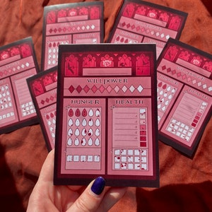 Puede incluir: Una hoja de personaje rosa y roja con las palabras "Will Power", "Hunger" y "Health" impresas en ella. La hoja tiene un dise&ntilde;o g&oacute;tico y se utiliza para rastrear las estad&iacute;sticas de los personajes en un juego de rol.