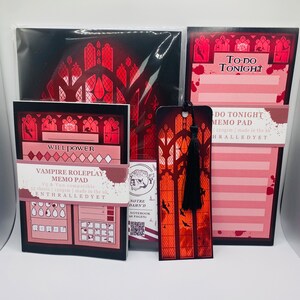 Puede incluir: Un conjunto de art&iacute;culos de papeler&iacute;a con tem&aacute;tica de Vampire Roleplay, que incluye una libreta de notas, un cuaderno y un marcap&aacute;ginas. La libreta de notas y el cuaderno presentan un dise&ntilde;o de ventana g&oacute;tica con un esquema de color rojo y negro. El marcap&aacute;ginas es un dise&ntilde;o de ventana g&oacute;tica negro y rojo con un borla negra.