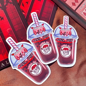May include: Three stickers of a vampire-themed bubble tea drink. Each sticker features a red and white striped straw, a clear cup with black tapioca pearls, and a red liquid. The cup has a white label with the text "VAMP FRIENDLY RECIPE" and a skull with red roses and bat wings. The text "BUBBLE TEA" is written in a circle around the skull.