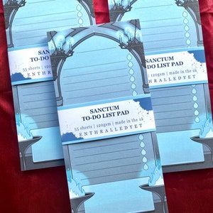 Puede incluir: Tres blocs de notas para hacer con un diseño de arco gótico, de color azul y gris. Cada bloc de notas contiene 55 hojas y tiene un gramaje de 120 g/m². El texto en el bloc de notas dice "Sanctum To-Do List Pad" y "Enthralled Yet".