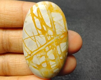 May include: A white and yellow oval cabochon gemstone with a unique pattern of yellow veins and lines.
