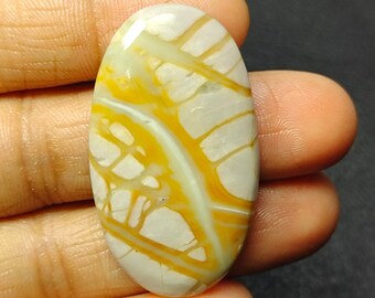 May include: Oval shaped cabochon gemstone with a white and yellow pattern. The stone has a smooth, polished surface.