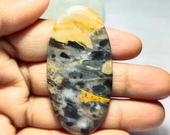 May include: A smooth, oval-shaped cabochon gemstone with a unique pattern of black, white, and yellow colours. The stone has a polished finish and is perfect for jewellery making.