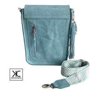 May include: A light blue leather crossbody bag with a zippered pocket and a fringe tassel. The bag has a long adjustable strap with a geometric pattern.