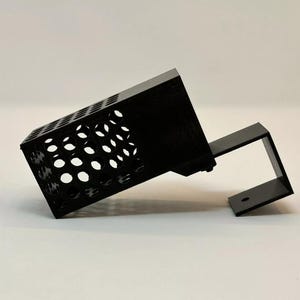 May include: A black plastic 3D printed object with a honeycomb pattern and a bracket. The object is designed to be mounted on a wall.