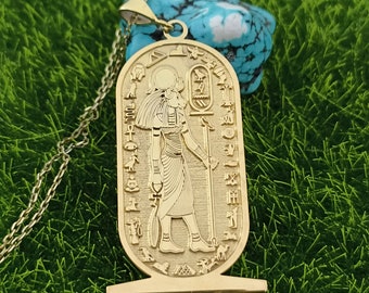 May include: Gold pendant necklace featuring an Egyptian god with hieroglyphics. The pendant is shaped like a scarab beetle and has a detailed design.