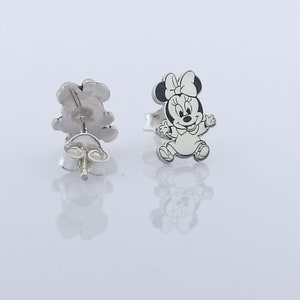 May include: A pair of silver stud earrings featuring a black and white cartoon image of Minnie Mouse. The earrings are designed with a post and butterfly back.