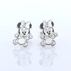 May include: A pair of silver stud earrings featuring a black and white cartoon image of Minnie Mouse.