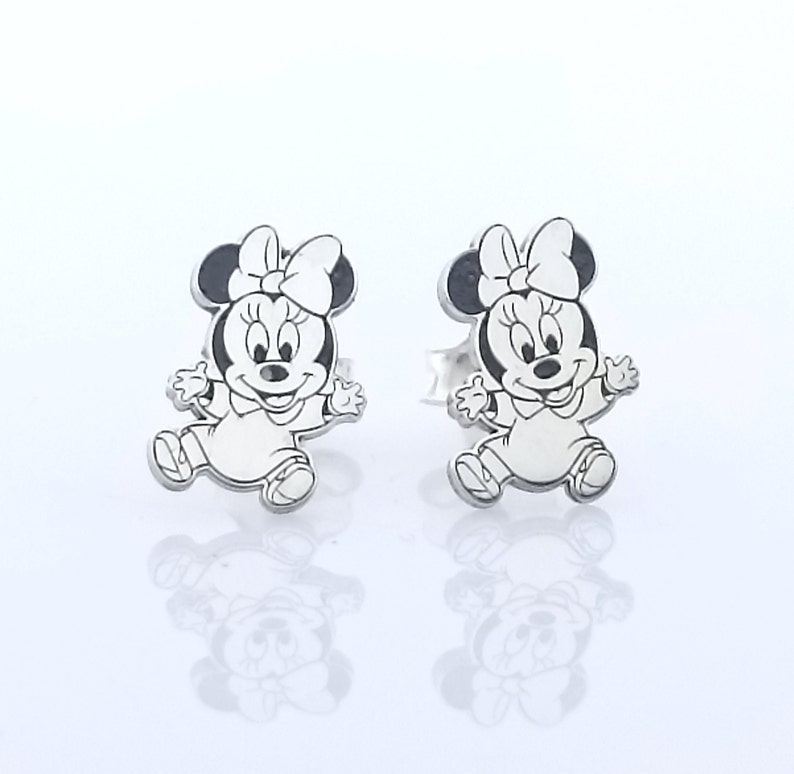 May include: A pair of silver stud earrings featuring a black and white cartoon image of Minnie Mouse.
