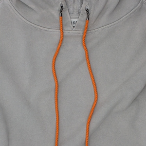 May include: A gray hooded sweatshirt with orange drawstrings. The drawstrings are made of a thick, braided cord.