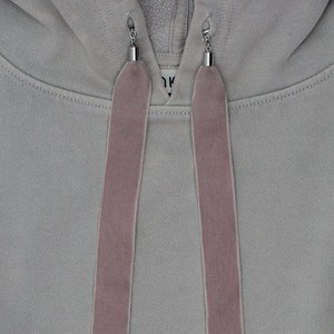 May include: A grey hooded sweatshirt with a drawstring featuring two long, dusty rose velvet ties.