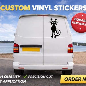 May include: A white ceramic mug with a black handle and the text "But First, Coffee" in a bold, black font. The mug is set against a blurred background. The mug appears to be approximately 10 cm tall.