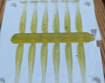 May include: A white plastic mold with 10 yellow and green soft plastic fishing lures. The lures are arranged in two rows of five.