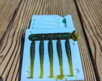 May include: A white plastic mold with six green and gold glitter fishing lures. The lures are in the mold and ready to be removed.