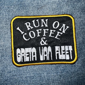 May include: Black and yellow embroidered patch with the text "I run on coffee & Greta Van Fleet".