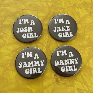 May include: Four round black buttons with white text. Each button says "I'm a [name] girl" with the names Josh, Jake, Sammy, and Danny.