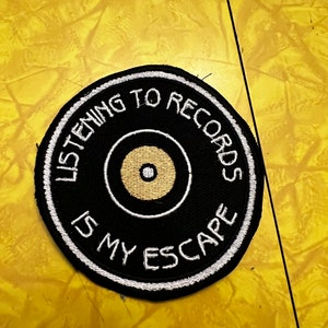 May include: Black and white embroidered patch with a record shape and the text "Listening to records is my escape".