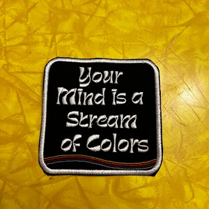 May include: Black embroidered patch with white text that reads "Your mind is a stream of colors".