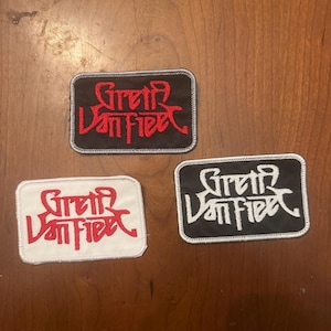 May include: Three rectangular embroidered patches featuring the text Greta Van Fleet. One patch has a black background with red text and a grey border. Another has a white background with red text and a white border. The third has a black background with white text and a white border.