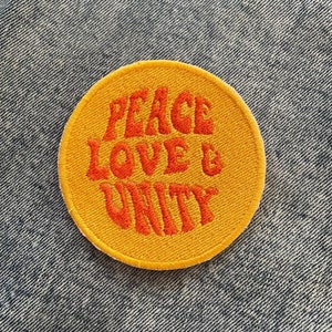 May include: A yellow circle patch with the words "Peace Love & Unity" in orange embroidered lettering.