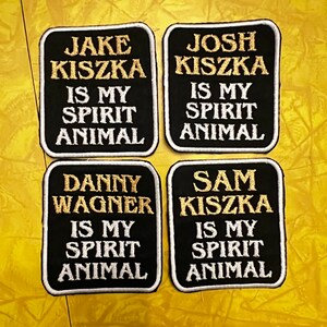 May include: Four black fabric patches with white and gold embroidery. The patches read "Jake Kiszka is my spirit animal", "Josh Kiszka is my spirit animal", "Danny Wagner is my spirit animal", and "Sam Kiszka is my spirit animal".