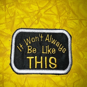 May include: Black and white embroidered patch with yellow stitching. The patch reads "It Won't Always Be Like THIS".