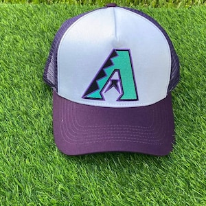 May include: A white and purple trucker hat with a green and purple Arizona Diamondbacks logo on the front.