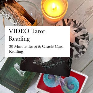 May include: A collection of items associated with tarot readings, including tarot cards, crystals, a lit candle, and sage. The image displays the text "VIDEO Tarot Reading" and "30 Minute Tarot & Oracle Card Reading". The items are arranged on a light wooden surface.