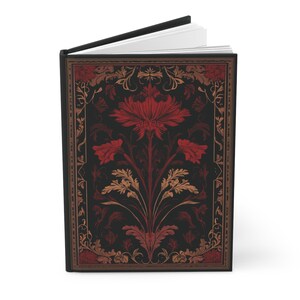 Op de afbeelding: Een hardcover journal met een zwarte rug. De omslag heeft een donkere achtergrond met een bloemenontwerp in rode, gouden en bruine tinten. Het bloemenontwerp bevat een grote centrale bloem en kleinere bloemen.