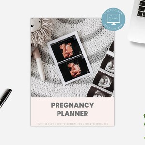 May include: A pregnancy planner with a pink and white cover. The cover features the text "Pregnancy Planner" and a photo of an ultrasound image. The planner is on a white surface with a stuffed animal and a pen.