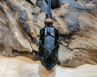 May include: Black obsidian crystal pendant with a black cord and wooden bead. The crystal is wrapped in a black macrame net.