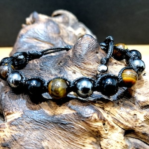 May include: A black cord bracelet with tiger's eye, black onyx, and hematite beads. The bracelet has a sliding knot closure.