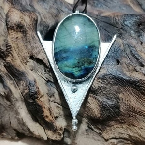 May include: A silver pendant with a triangular design features a large oval-shaped labradorite gemstone with iridescent blue, green, and gold hues.
