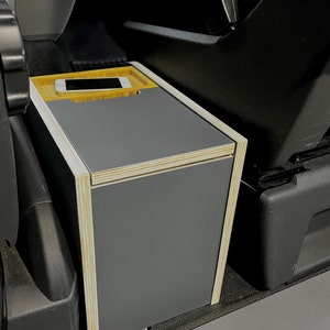 Puede incluir: Una caja de almacenamiento gris con un marco de madera y una peque&ntilde;a bandeja de madera en la parte superior. La bandeja tiene un tel&eacute;fono m&oacute;vil.